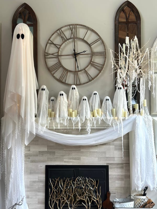 Mantel with a row of cheesecloth ghosts and candles beside a large clock